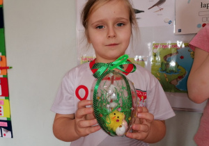 Dziewczynka pokazuje stworzoną dekorację z akrylowego jajka.